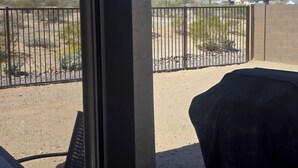 A view from a window overlooking a fenced outdoor area with desert vegetation and mountains in the background. - Pleasant 3-bedroom house with AC in San Tan Valley (San Tan Valley)