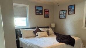 Une chambre à coucher avec un lit, un ventilateur de plafond et des tableaux accrochés au mur.
