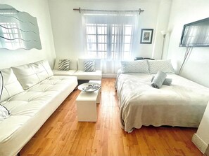 A modern, well-lit bedroom with a sofa, a bed, and a small table. - Awesome Location Heart of South Beach -Walk to Beach, Shops & Nightlife (Miami Beach)