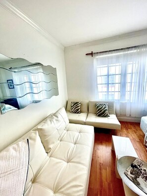 A living room with a beige sofa, a coffee table, and a large mirror on the wall. - Awesome Location Heart of South Beach -Walk to Beach, Shops & Nightlife (Miami Beach)