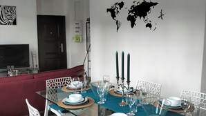 A modern dining area with a glass table, white chairs, and a teal tablecloth. - Glamorous flat in Mertzwiller (Mertzwiller)