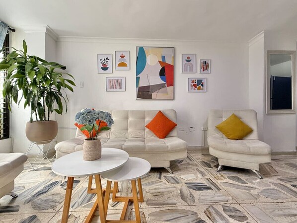 A living room with a white sofa, a round coffee table, and a potted plant.