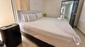 A hotel room with a bed, a bedside table, a mirror, and a window. - Medellín Poblado Gem • Steps to Cafés & Nightlife (Medellín)
