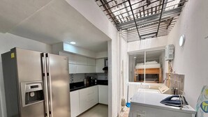 A compact kitchen with stainless steel appliances, a built-in oven, and a small laundry area. - Medellín Poblado Gem • Steps to Cafés & Nightlife (Medellín)
