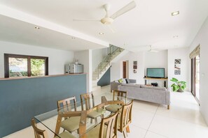 A modern living space with a dining area, a sofa, a TV, and a staircase. - Serene Bay View Villa in Ko Samui - Your Tropical Paradise (Koh Samui)