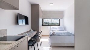 Een moderne hotelkamer met een bed, een bureau met een flatscreen-televisie en een raam met uitzicht op de stad.