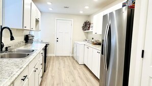 A modern kitchen with white cabinets, a stainless steel refrigerator, and a granite countertop. - Clean, Cute, and Comfortable (Safford)