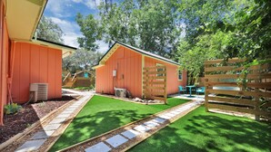 A fenced backyard with artificial grass, a wooden deck, and a small shed. - The Tropical Palms ~ Cowboy Pool ~ Private yard. (St. Augustine)