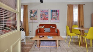 A room with a sofa, a table, and yellow chairs. There are three framed artworks on the wall. - The Tropical Palms ~ Cowboy Pool ~ Private yard. (St. Augustine)