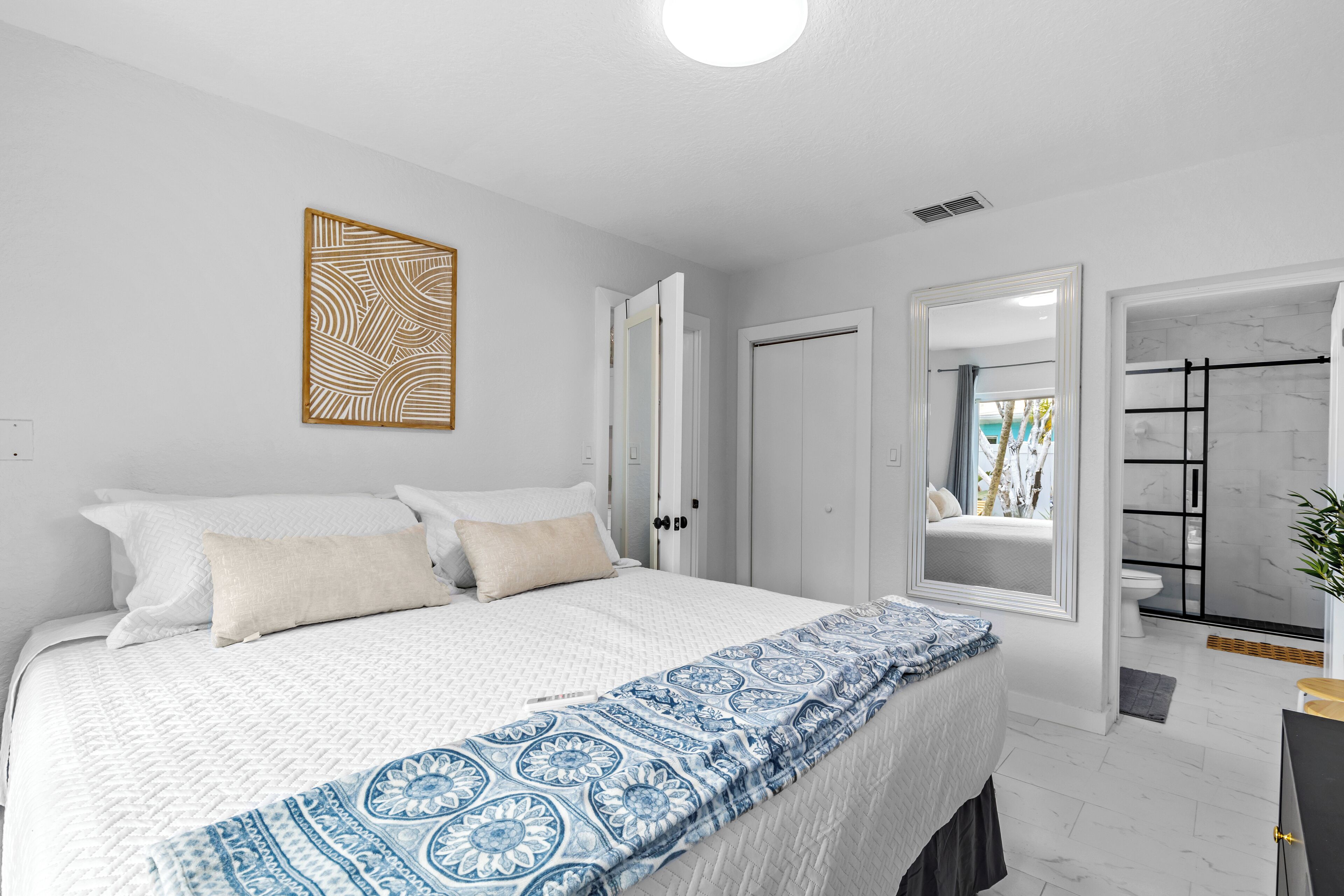 Une chambre à coucher moderne avec un grand lit, un plaid à motifs et une vue sur la salle de bain.
