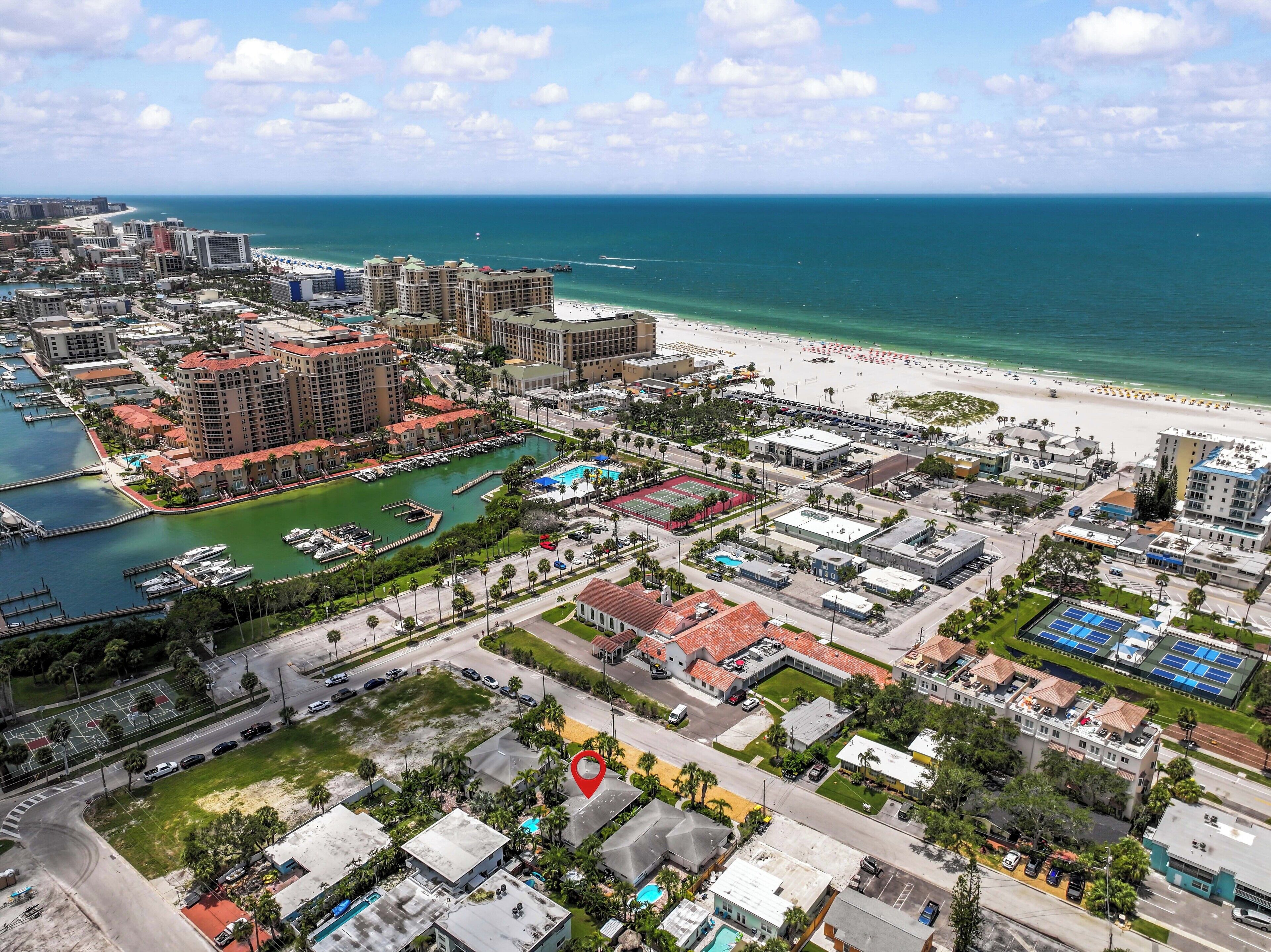 An aerial view of a coastal city with a marina, beachfront, and high-rise buildings.