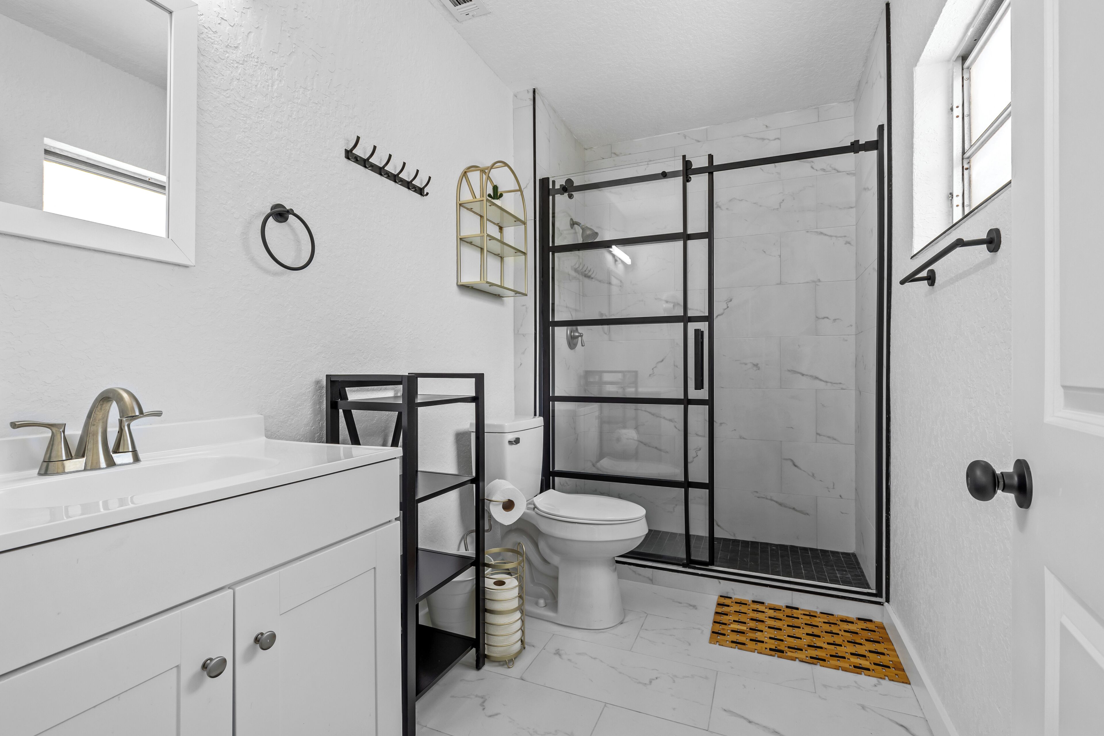 Une salle de bain moderne avec un lavabo blanc, des toilettes et une douche à parois de verre.