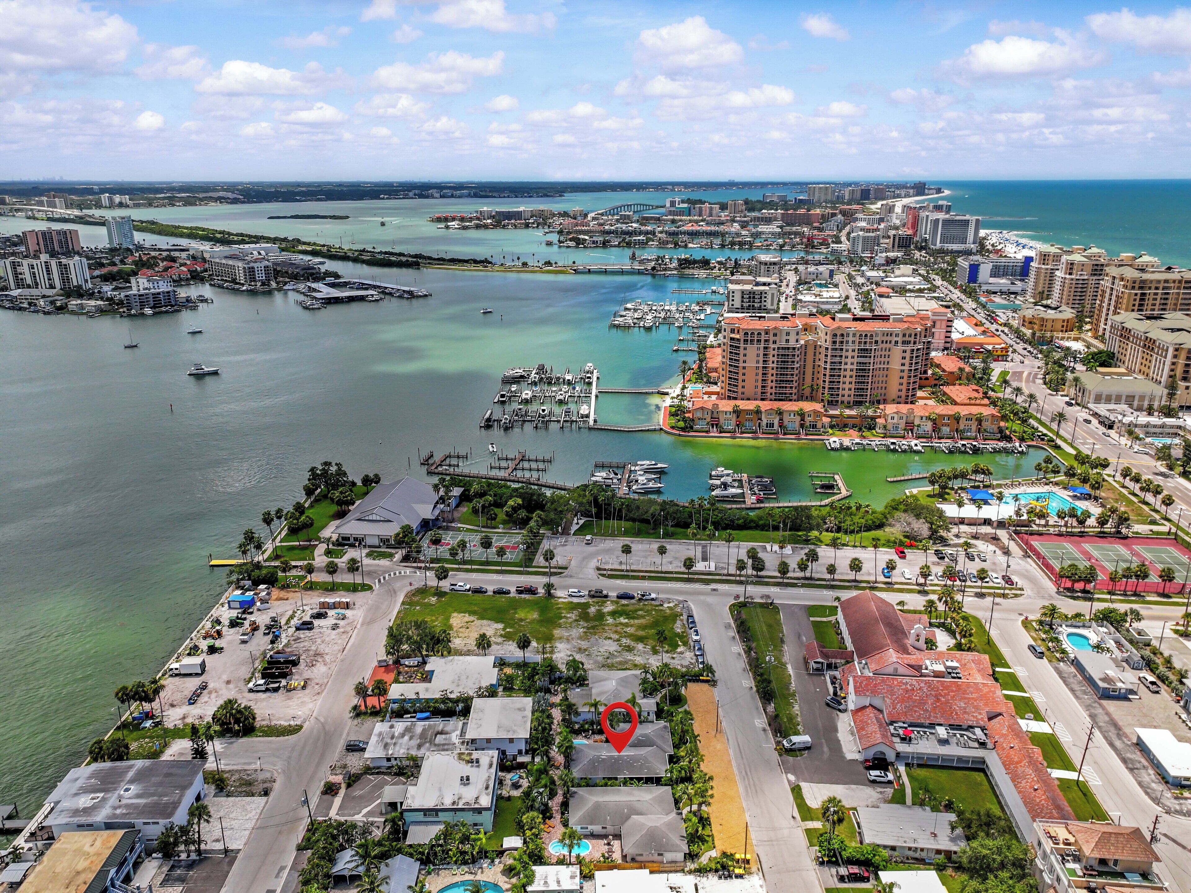 Vue aérienne d’une ville côtière avec un port de plaisance, des hôtels et un grand complexe hôtelier doté d’une piscine.