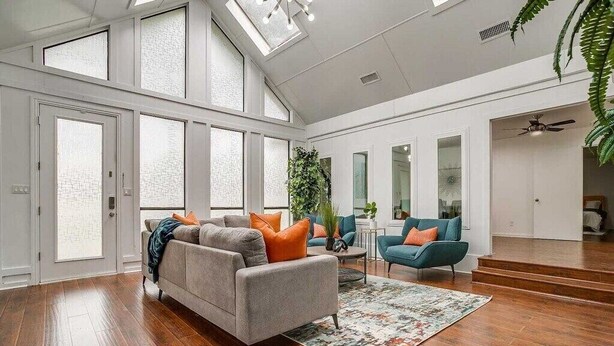 A spacious living room with a grey sofa, teal armchairs, and a wooden floor. - Spacious 6-bedroom house in delightful Grand Prairie with Pool (Grand Prairie)