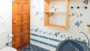 A bathroom with a wooden door, a toilet, a sink with a blue basin, and a shelf with a plant. - Faratea Bayhouse - Seaside, large garden, unique panoramic view. (Moorea)