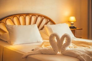 A bed with white bedding, a wooden headboard, and a nightstand with a lamp. - Faratea Bayhouse - Seaside, large garden, unique panoramic view. (Moorea)
