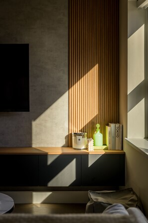 Une chambre moderne dotée d’une banquette intégrée, d’un téléviseur fixé au mur et d’une fenêtre laissant entrer la lumière naturelle.