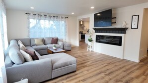 Una sala de estar moderna con un sofá seccional gris, una mesa de centro de madera y una chimenea.