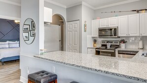 Una cocina moderna con armarios blancos, encimera de granito y electrodomésticos de acero inoxidable.