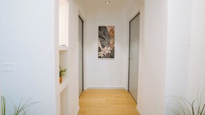 Un pasillo con suelo de madera, paredes blancas y una obra de arte enmarcada en la pared.