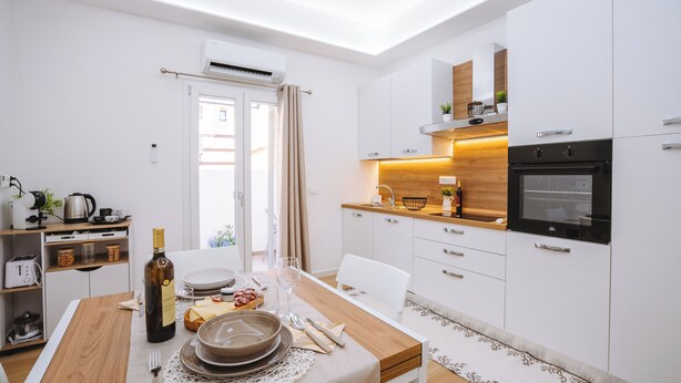 Una cocina moderna con armarios blancos, encimera de madera y horno empotrado.