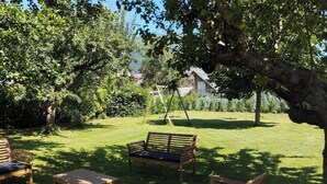 Un espacio al aire libre con césped, bancos de madera y un arenero.