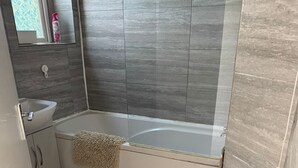 Een badkamer met een bad, wastafel en spiegel.