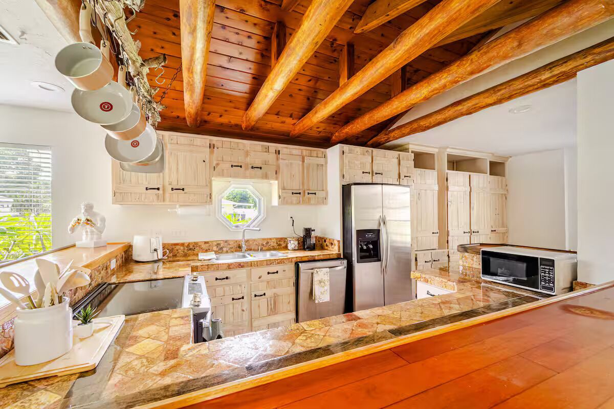 Una cocina moderna con vigas de madera, encimeras de granito y electrodomésticos de acero inoxidable.