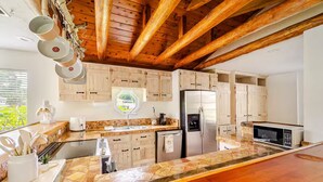 Eine moderne Küche mit Holzbalken, Granit Arbeitsplatten und Edelstahlgeräten.