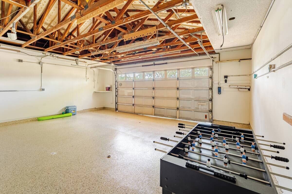 A spacious indoor area with a foosball table, a garage door, and exposed wooden beams.
