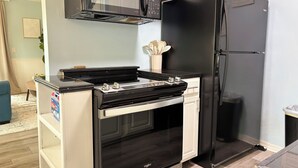 A compact kitchen with a black stove, a microwave, and a black refrigerator.