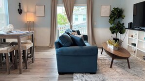 A living room with a blue sofa, wooden dining table, and a ceiling fan.
