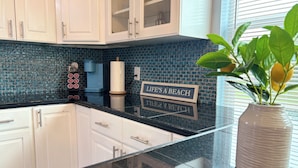 A kitchen with white cabinets, a blue backsplash, and a sign that reads "LIFE'S A BEACH".