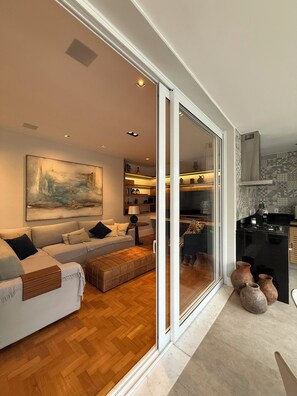 A modern living room with a sofa, ottoman, and a large painting.
