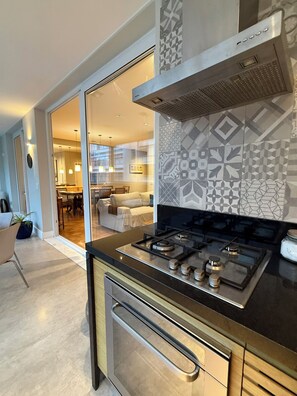 A modern kitchen with a gas stove, stainless steel appliances, and a patterned backsplash.