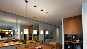 A modern kitchen with a wooden dining table, pendant lights, and a built-in wine fridge. - Copacabana 3BR • 1 Block to the Beach — Stylish & Family-Friendly (Rio de Janeiro)