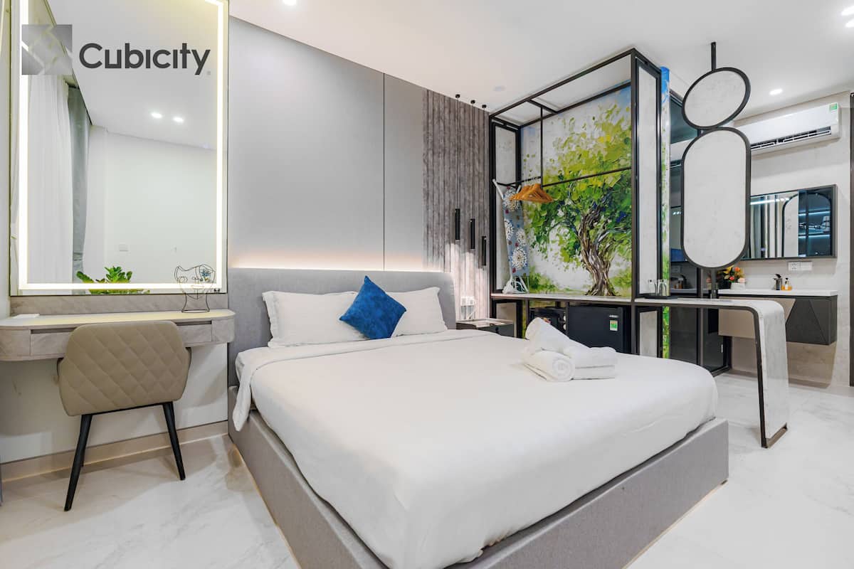 Une chambre d’hôtel moderne dotée d’un grand lit, d’un bureau, d’une chaise, d’un miroir et d’un mur orné d’une œuvre d’art sur le thème de la nature.