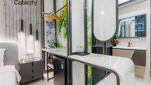 A modern hotel room with a marble countertop, a bed, a wardrobe, and a bathroom with a large mirror and sink. - Cubicity Pho Duc Chinh (Ho Chi Minh Municipality)