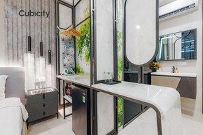 Ein modernes Hotelzimmer mit Marmorplatte, einem Bett, einem Kleiderschrank und einem Badezimmer mit großem Spiegel und Waschbecken.