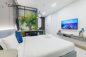 Ein modernes Hotelzimmer mit einem großen Bett, einem flachbildfernseher an der Wand und einem Baumgemälde.