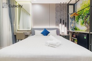 Ein modernes Hotelzimmer mit einem großen Bett, einem Schreibtisch, einem Spiegel und einem an der Wand befestigten Fernseher.