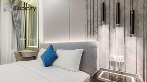 A modern hotel room with a bed, a bedside table, and a nightstand with a charging station. - Cubicity Pho Duc Chinh (Ho Chi Minh Municipality)
