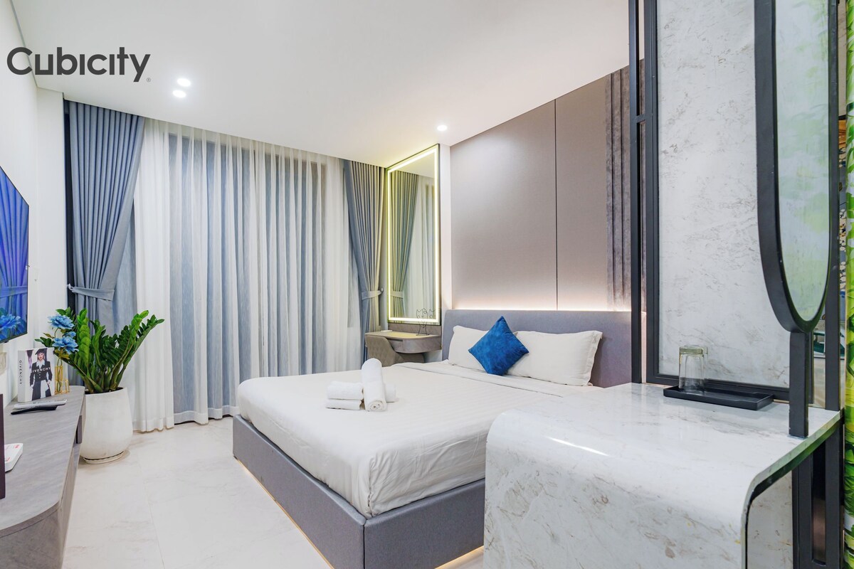 Una habitación de hotel moderna con una cama grande, un escritorio, un televisor y una planta en maceta.