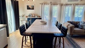 Een ruime eetruimte met een lange tafel, zwarte stoelen en een kroonluchter.