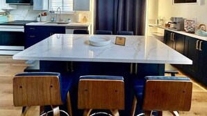 Een moderne keuken met een houten plafond, een centraal kookeiland met barkrukken, en een eethoek.
