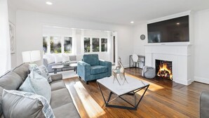 A modern living room with a fireplace, a large TV, and a sofa. - Elegant 4BR Oasis in Atlanta! (Atlanta)