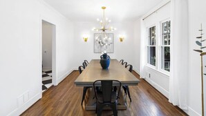 A dining room with a long table, black chairs, a blue vase centerpiece, a chandelier, and a painting on the wall. - Elegant 4BR Oasis in Atlanta! (Atlanta)