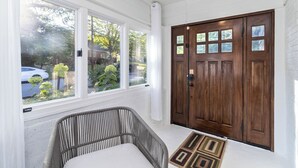 A room with a large window, a wooden door, and a wicker chair. - Elegant 4BR Oasis in Atlanta! (Atlanta)