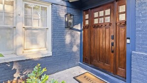 A house with a blue exterior, a wooden front door with a glass panel, and a window with a white frame. - Elegant 4BR Oasis in Atlanta! (Atlanta)