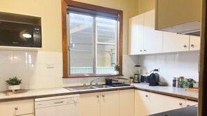 A compact kitchen with white cabinets, a dishwasher, a microwave, a window, and a sink.